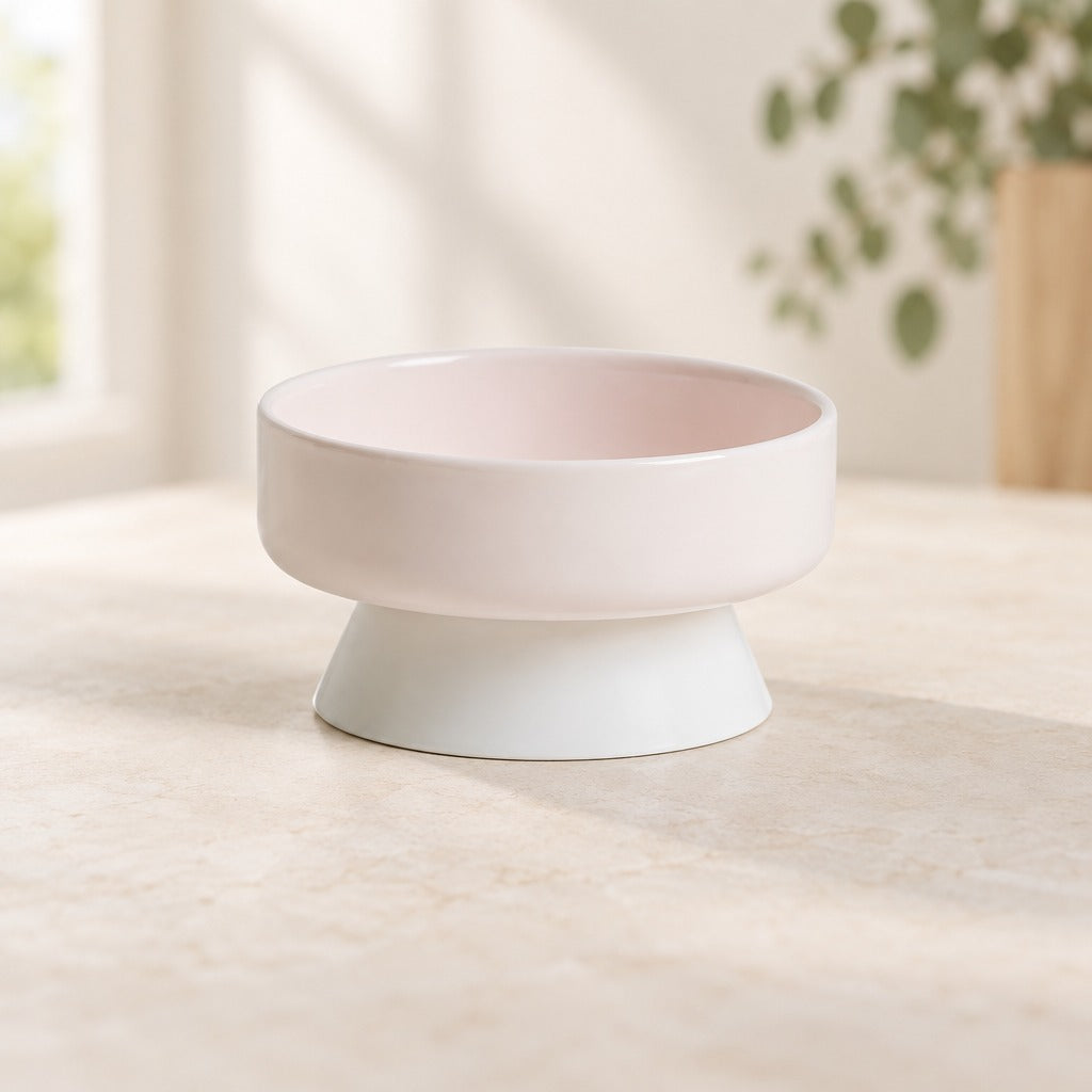 Le bol surélevé rose poudré, modèle bol creux, seul sur un plan clair, vu de trois quarts.
