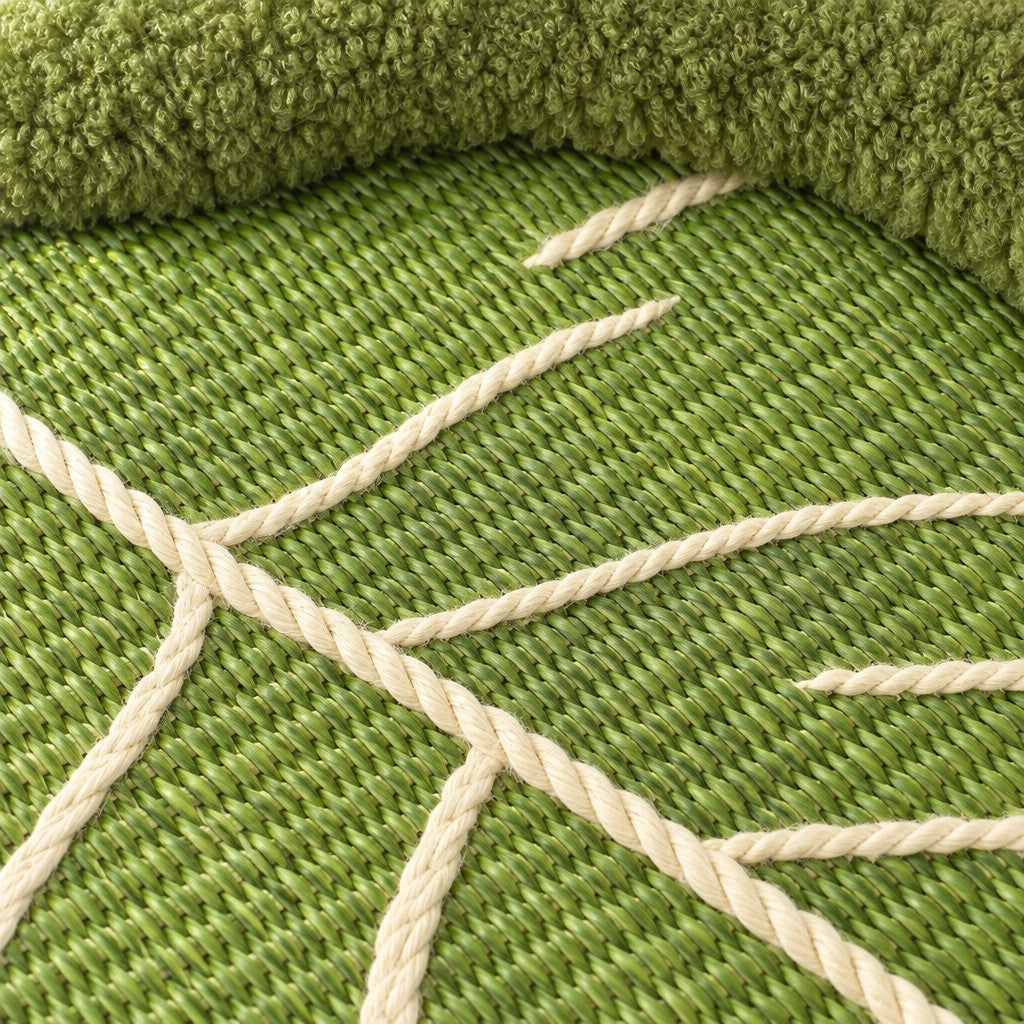 Gros plan sur le tissage vert du couchage et les cordons crème cousus en nervures, avec le bourrelet bouclé vert au bord du cadre.
