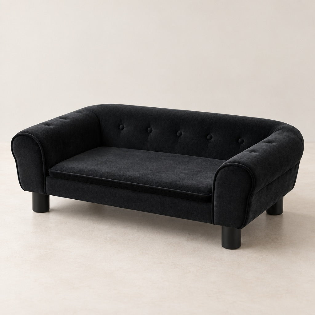 Le canapé pour chien en velours noir seul de trois quarts, dossier capitonné, accoudoirs roulés, coussin plat et quatre pieds.