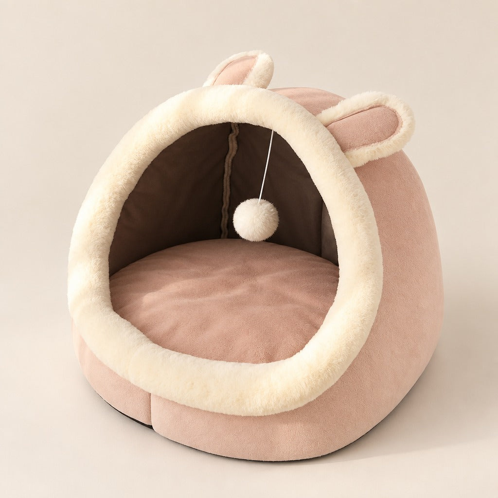Cocon pour chat rose poudré vu de trois quarts, bourrelet ivoire et coussin rose.