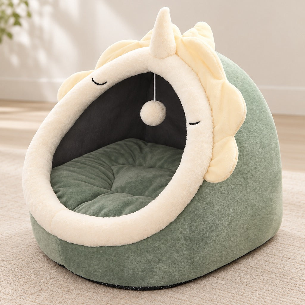 Cocon pour chat vert sauge vu de trois quarts, crête de pétales ivoire et coussin vert.