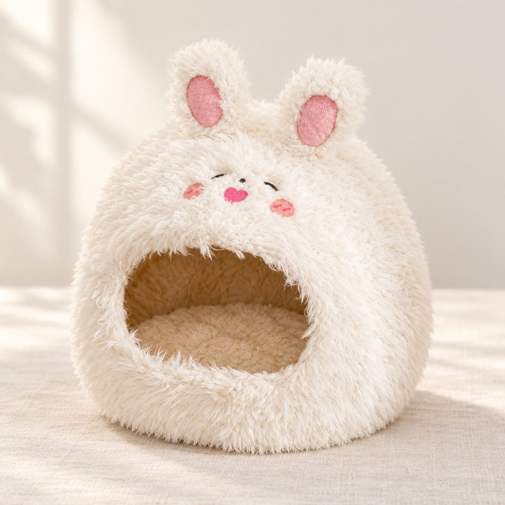 Le cocon écru lapin seul sur fond clair, ses deux longues oreilles doublées de rose dressées au sommet.