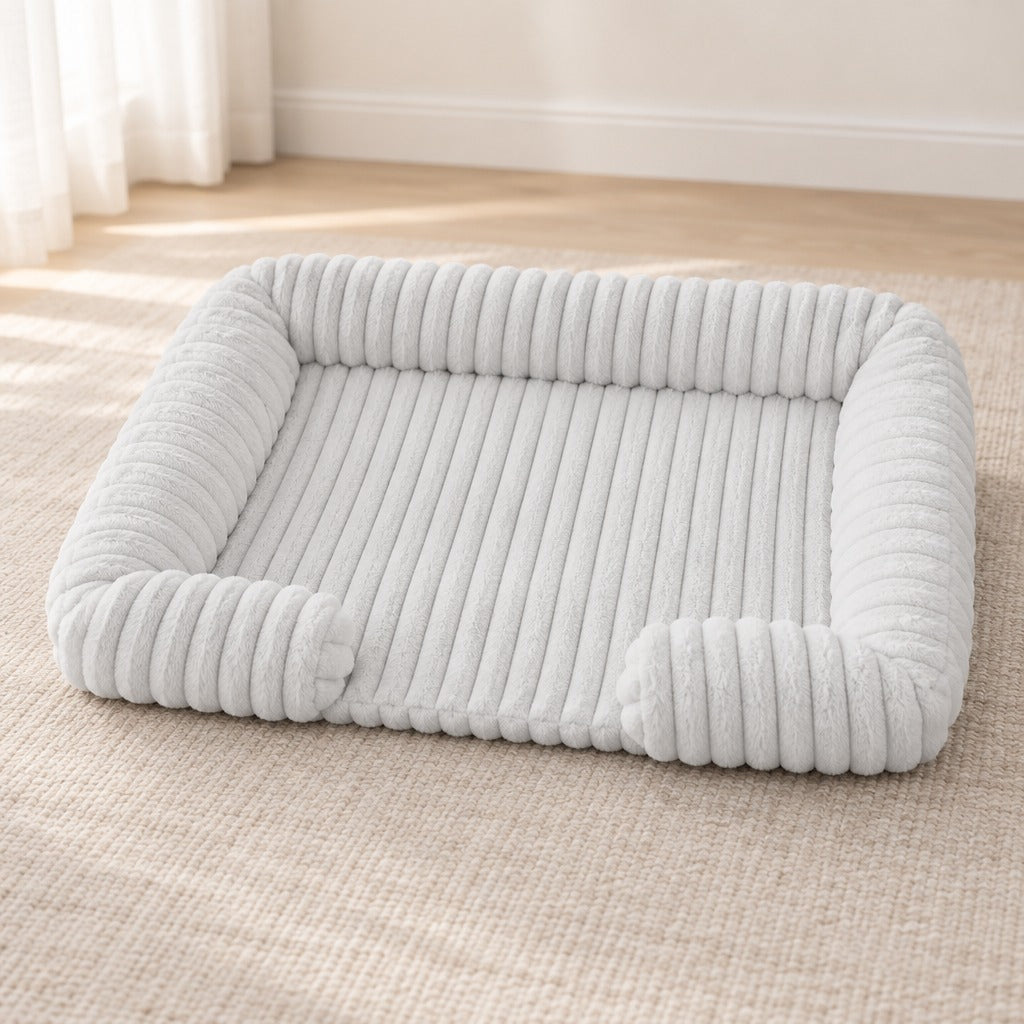 Corbeille pour chien coloris blanc perle, seule sur un tapis clair, bourrelet haut sur trois côtés.