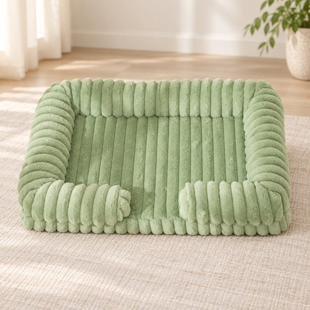 Corbeille pour chien coloris vert sauge, seule sur un tapis clair dans un séjour lumineux.