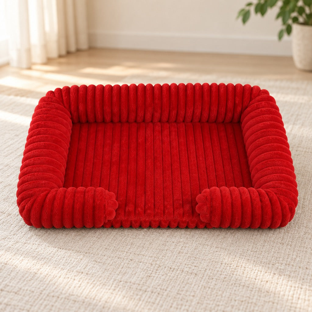 Corbeille pour chien coloris rouge carmin, seule sur un tapis écru devant une plinthe blanche.