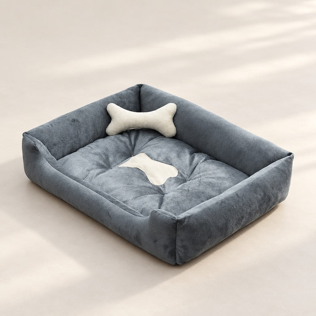 La corbeille gris anthracite et gris perle seule sur fond clair, son coussin en forme d'os ivoire posé contre le bord du fond.