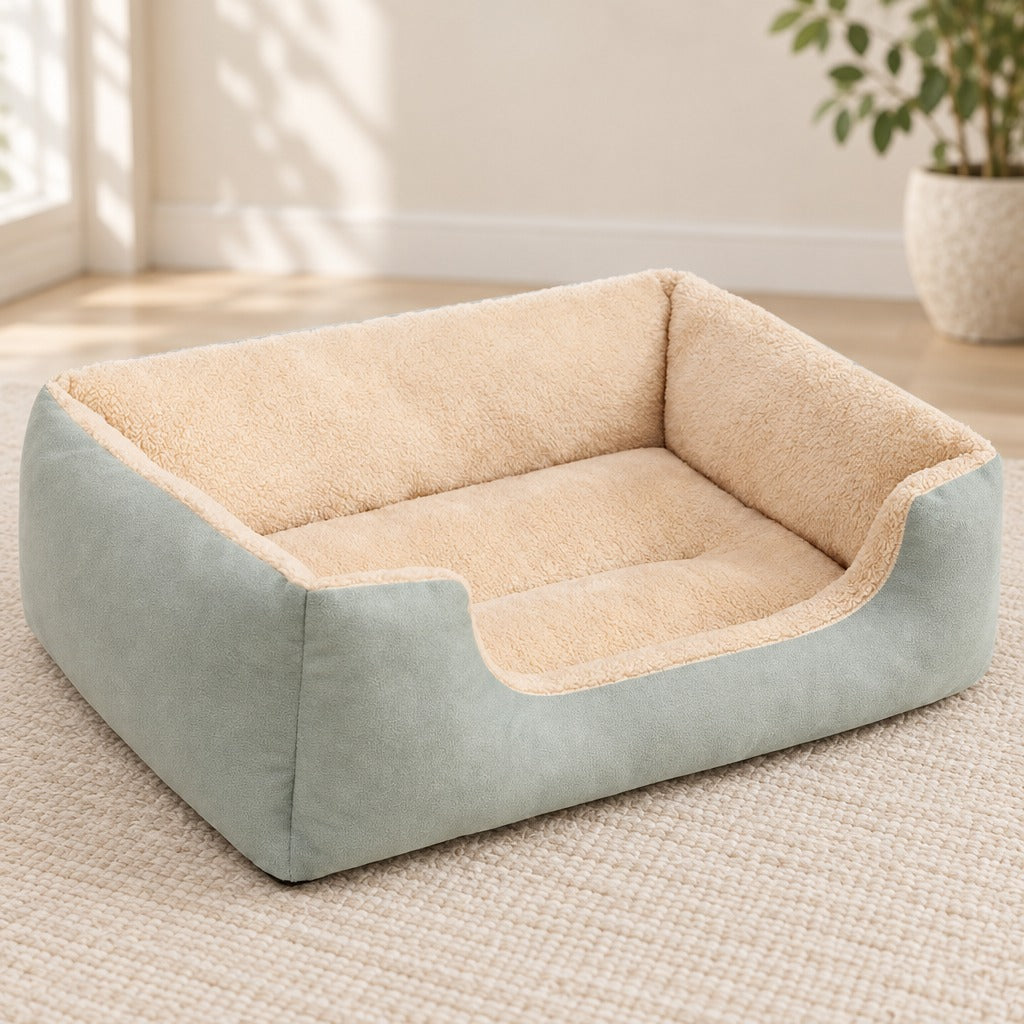 Corbeille moelleuse vert céladon posée seule sur un tapis clair, ses trois parois hautes encadrant le couchage en peluche bouclée.
