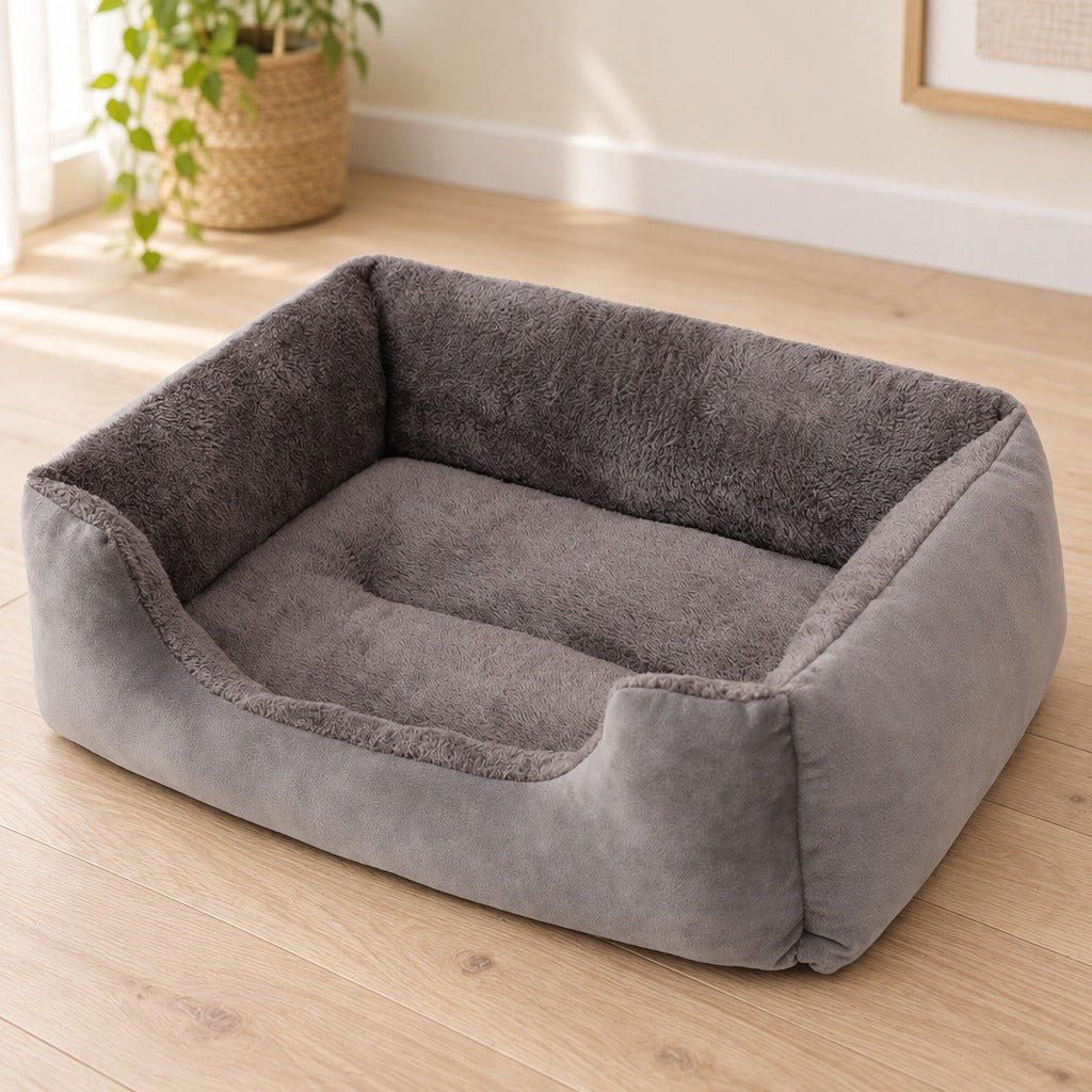Corbeille moelleuse grise posée seule sur un parquet clair, vue de haut sur son couchage plat en peluche.
