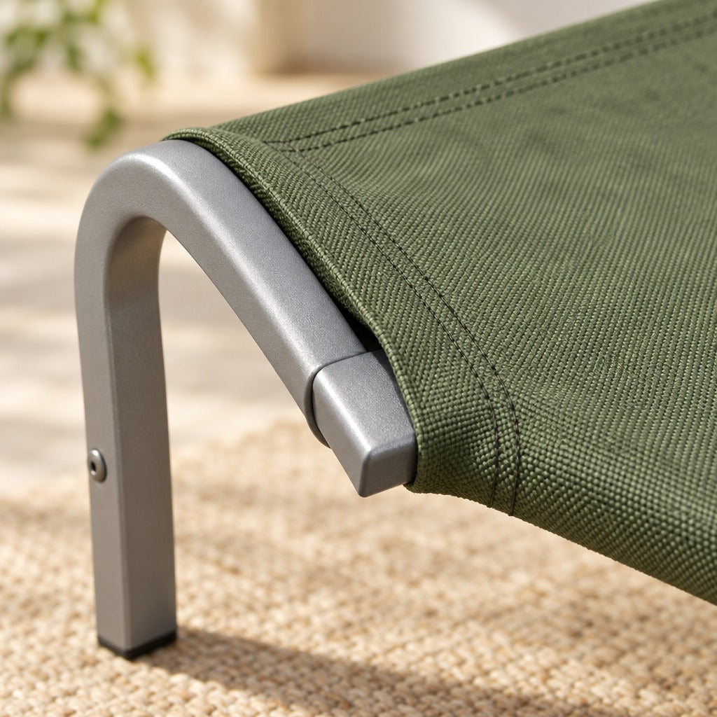 Gros plan sur un angle du couchage vert kaki : l'ourlet surpiqué de la toile enfilé sur le tube métallique cintré et l'about du tube qui en ressort.