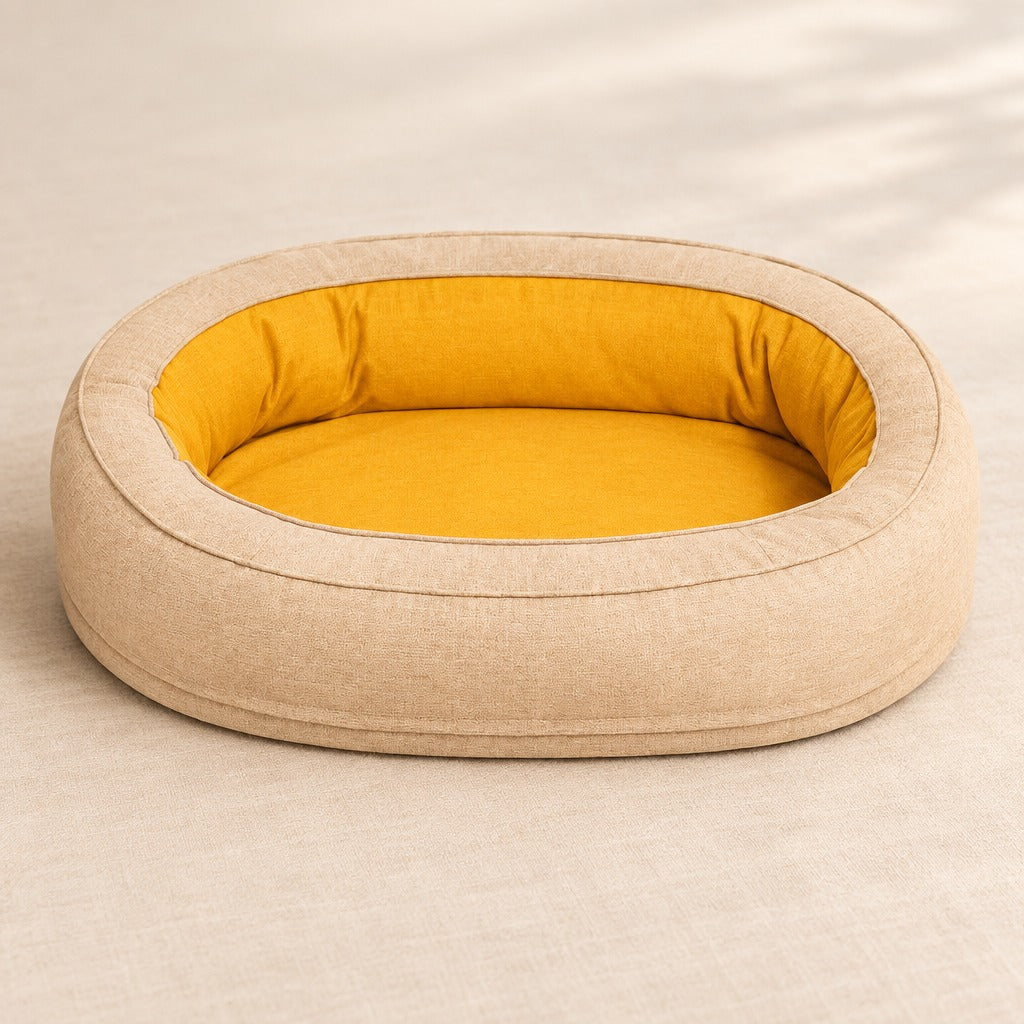 Le couchage ovale sable en tissu tissé mat, seul, vu de trois quarts, son boudin continu et son couchage plat moutarde.