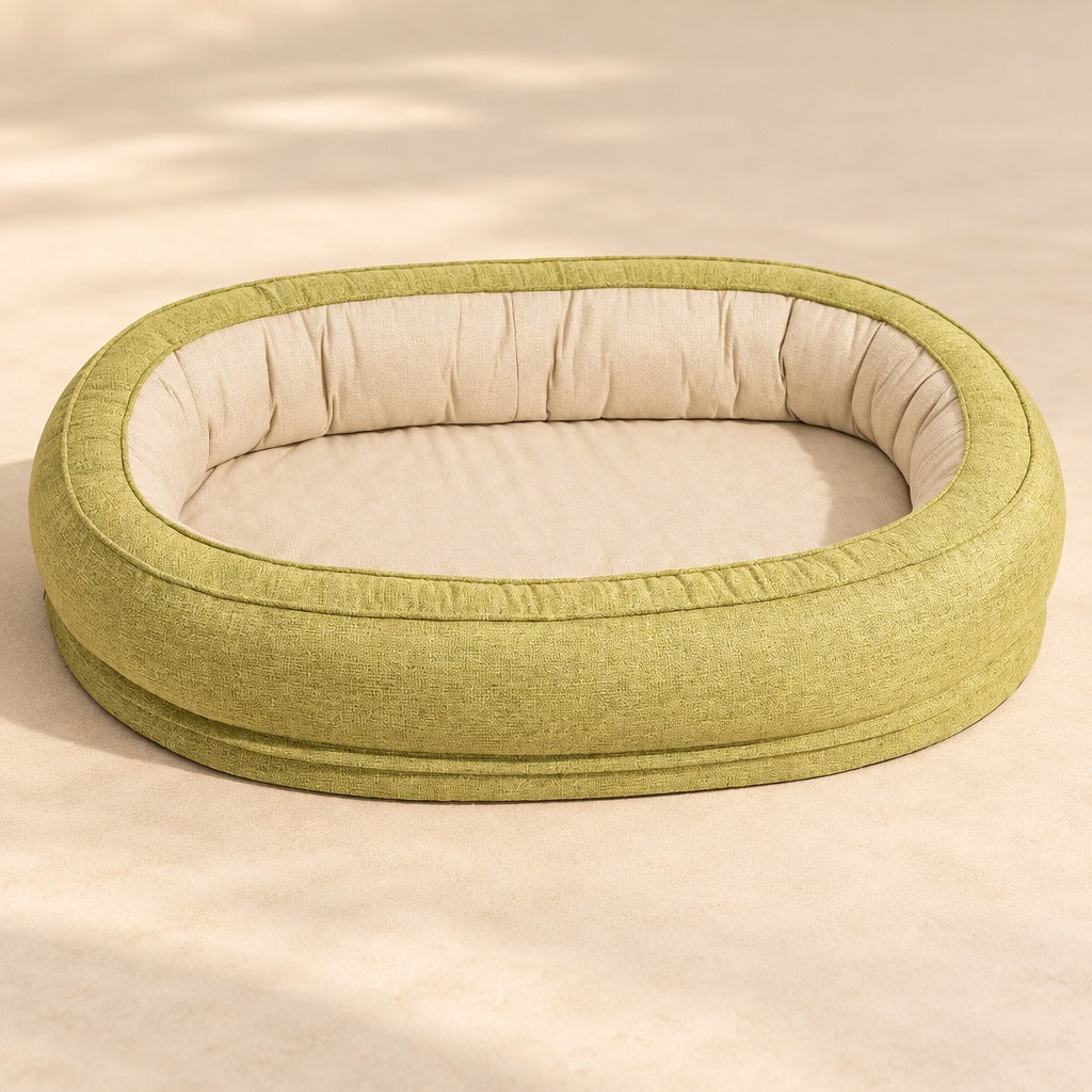 Le couchage ovale tilleul en tissu tissé mat, seul, vu de trois quarts, son boudin de hauteur constante et son couchage plat crème.