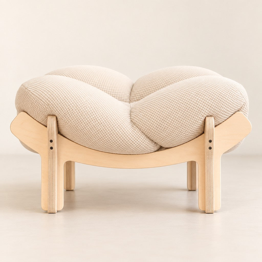 Le couchage seul vu de face, le coussin écru à quatre lobes posé sur le piètement en bois clair à quatre pieds.