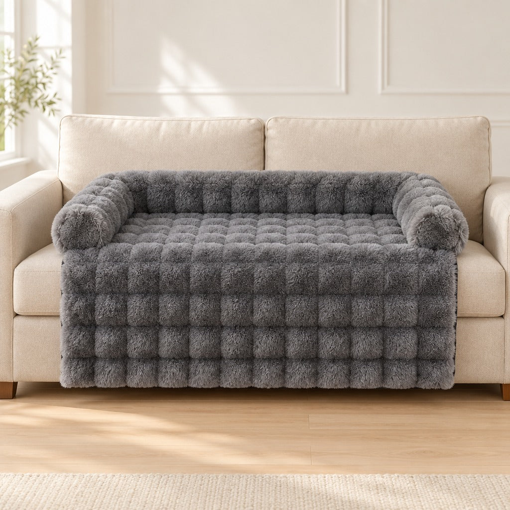 Le couchage de canapé gris anthracite seul, posé sur l'assise d'un canapé clair, le tablier retombant sur la façade.