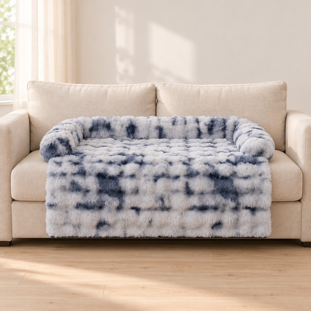 Le couchage de canapé bleu marbré seul sur un canapé clair, vu de face, le tablier retombant sur la façade.