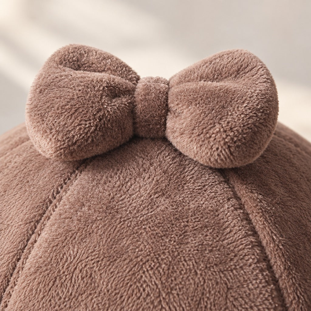Gros plan sur le nœud en peluche cousu au sommet du dôme brun cacao et sur les coutures fines de deux arêtes.