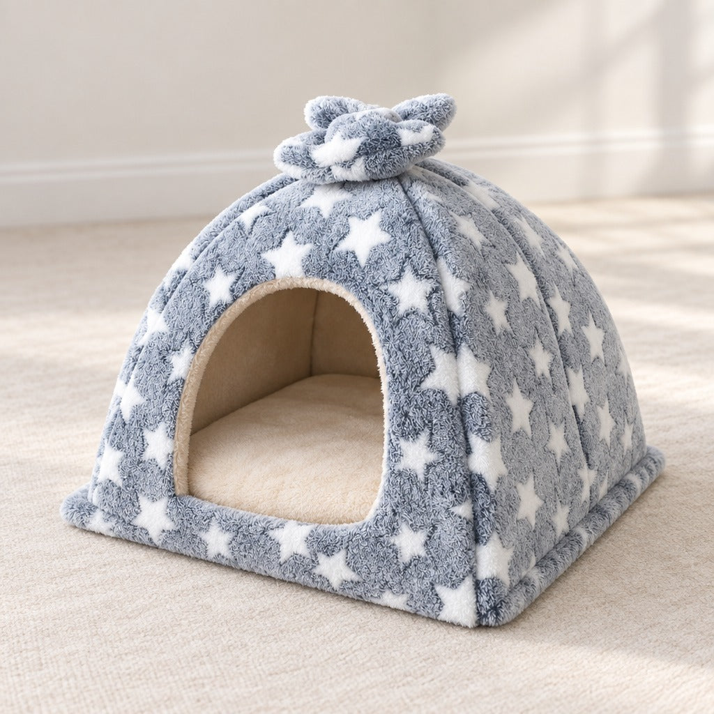 Le dôme en peluche gris étoilé vu de trois quarts, semé d'étoiles blanches, avec son nœud au sommet et son coussin crème au fond.