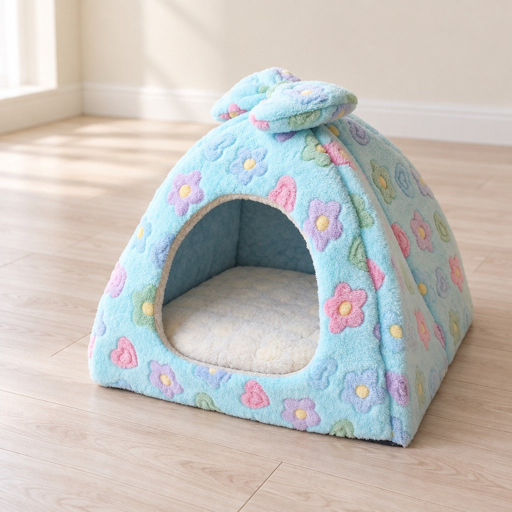 Le dôme en peluche bleu fleuri vu de trois quarts sur un parquet clair, fleurs pastel sur toute la coque et nœud au sommet.