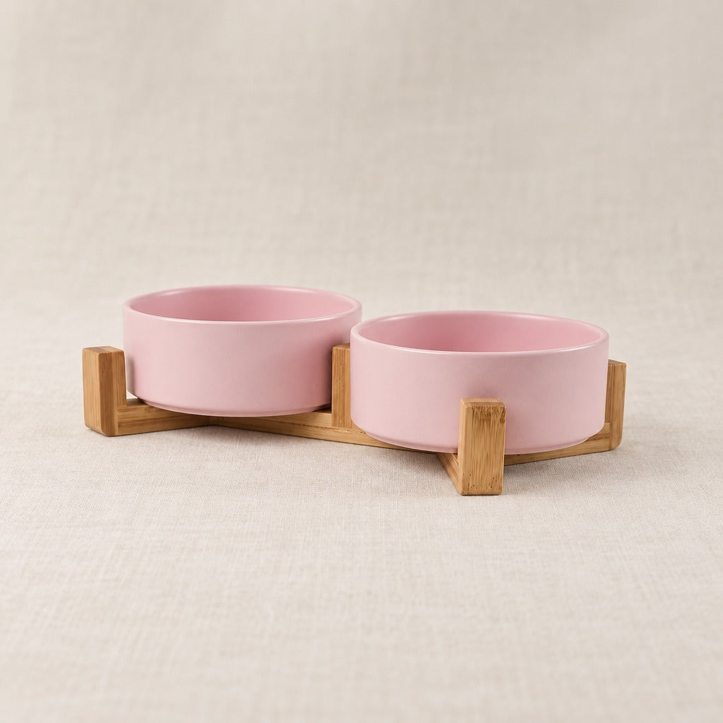 Duo de bols rose poudré dans son socle de bois clair, seul sur un fond clair, vu de trois quarts.