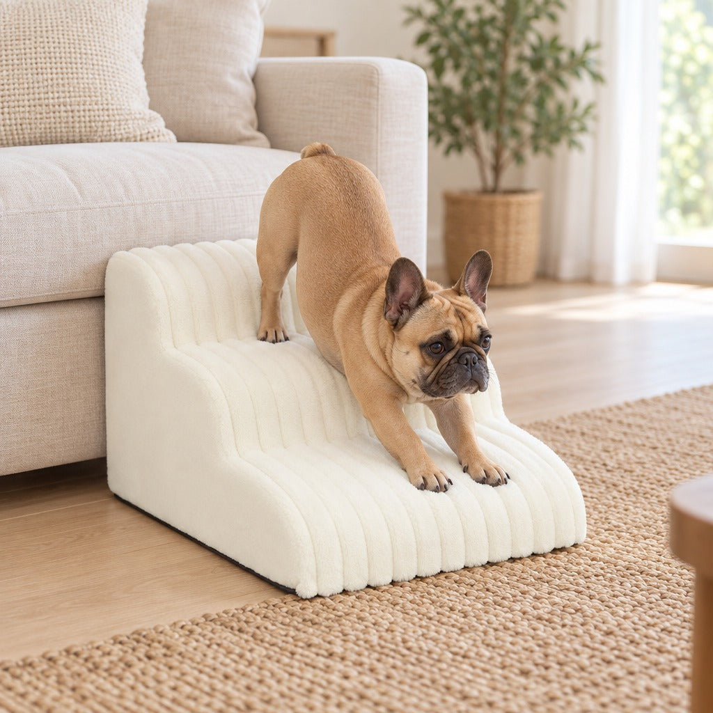 Un bouledogue français fauve s'étire sur les marches de l'escalier blanc crème posé contre un canapé en lin dans un salon clair.
