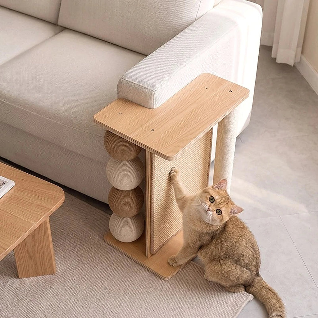 Le griffoir en bois naturel calé contre le bout de l'accoudoir du canapé, un chat roux dressé qui griffe la natte tressée.