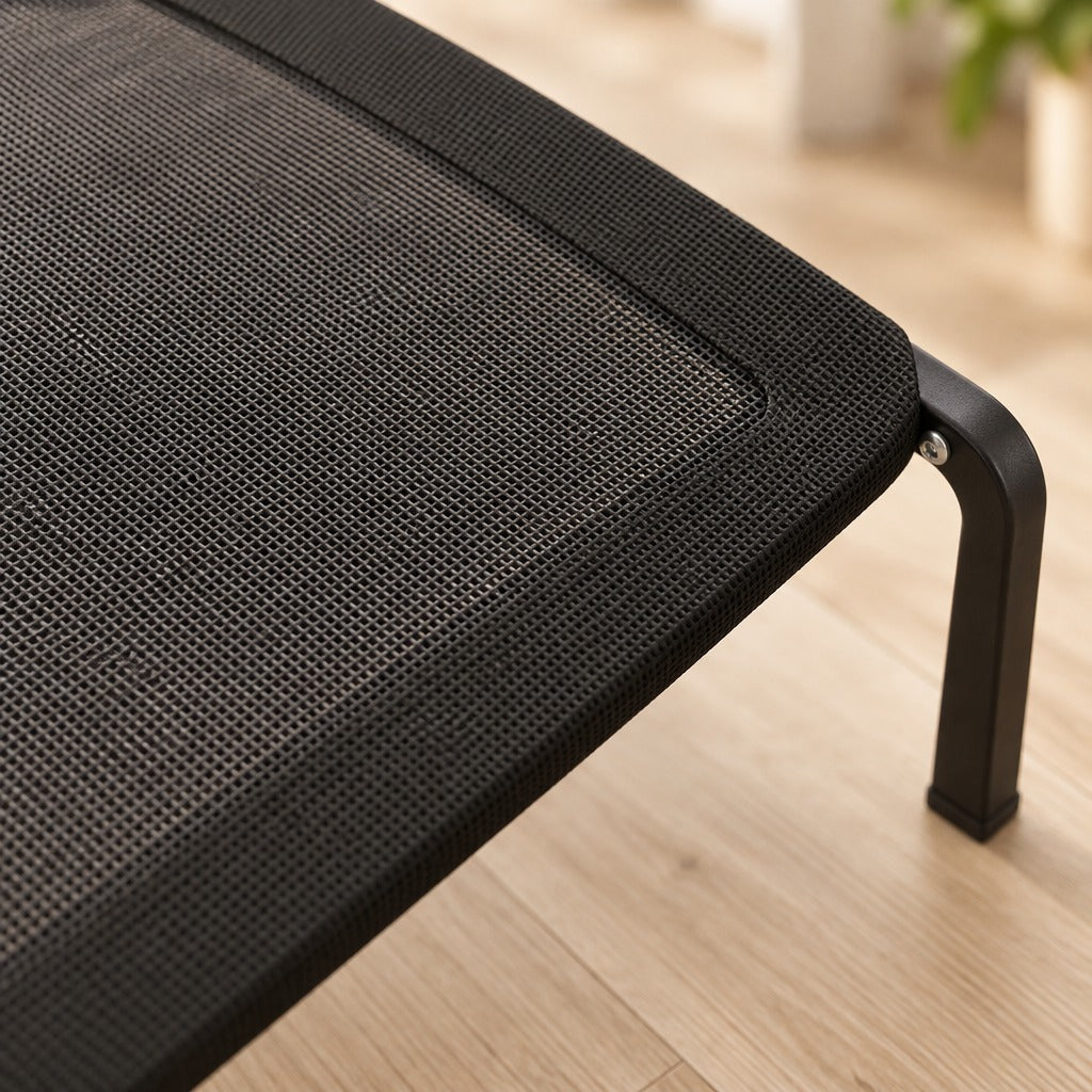 Gros plan d'un angle du lit de camp noir pour chien, toile maillée tendue, bandeau tissé et pied coudé vissé au cadre.