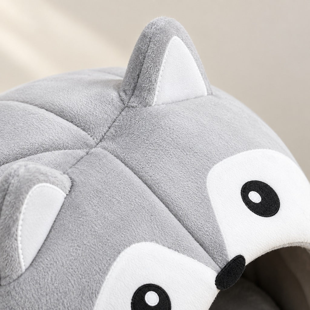 Gros plan sur la peluche à poil ras gris perle de la maison caverne pour chat, sur une oreille triangulaire doublée de clair et sur les coutures de la calotte.