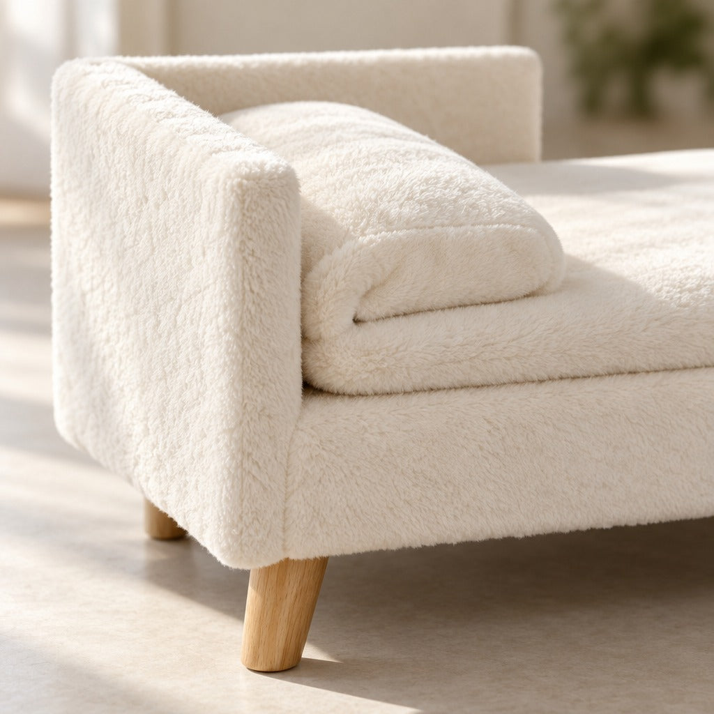 Gros plan sur la peluche ivoire du dossier en L de la méridienne et sur un pied rond en bois clair.