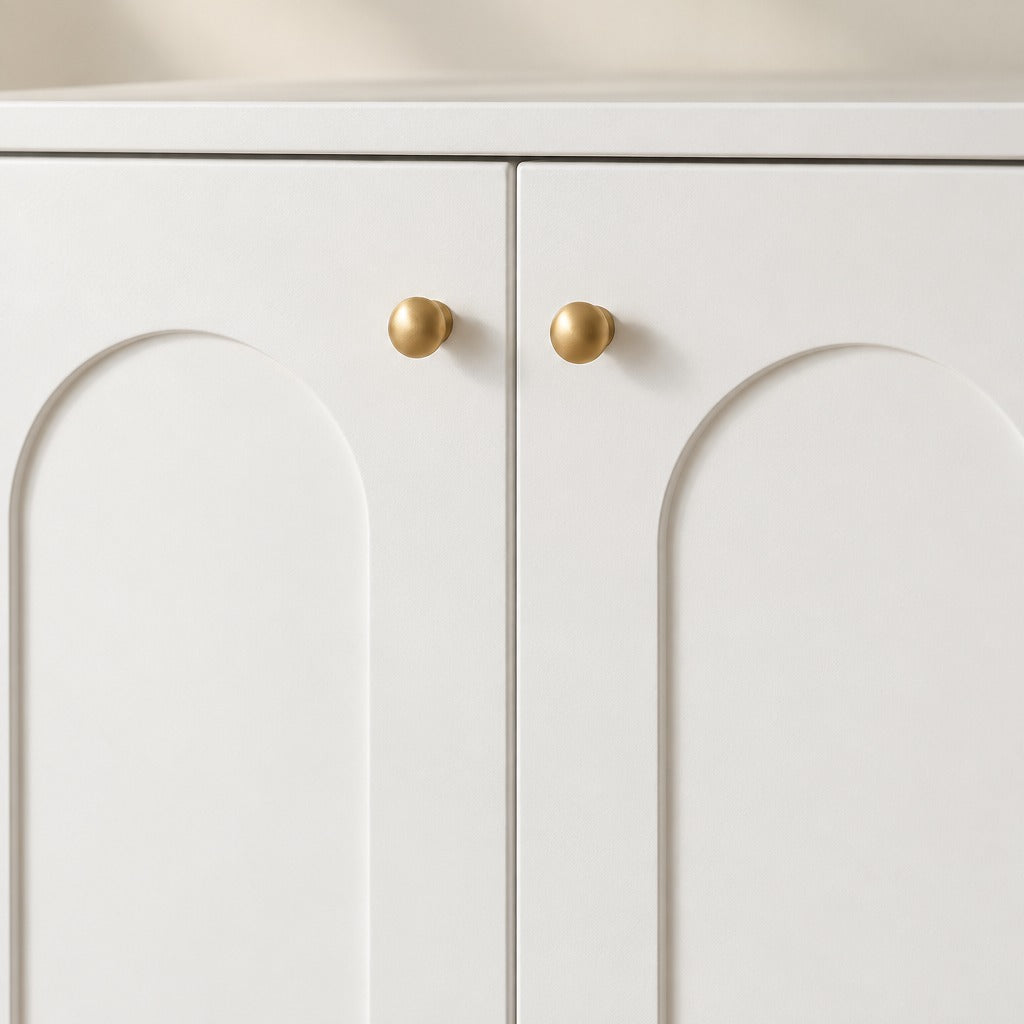 Gros plan sur les deux portes blanches à panneau en arche et les deux boutons dorés du meuble à litière pour chat blanc et doré.