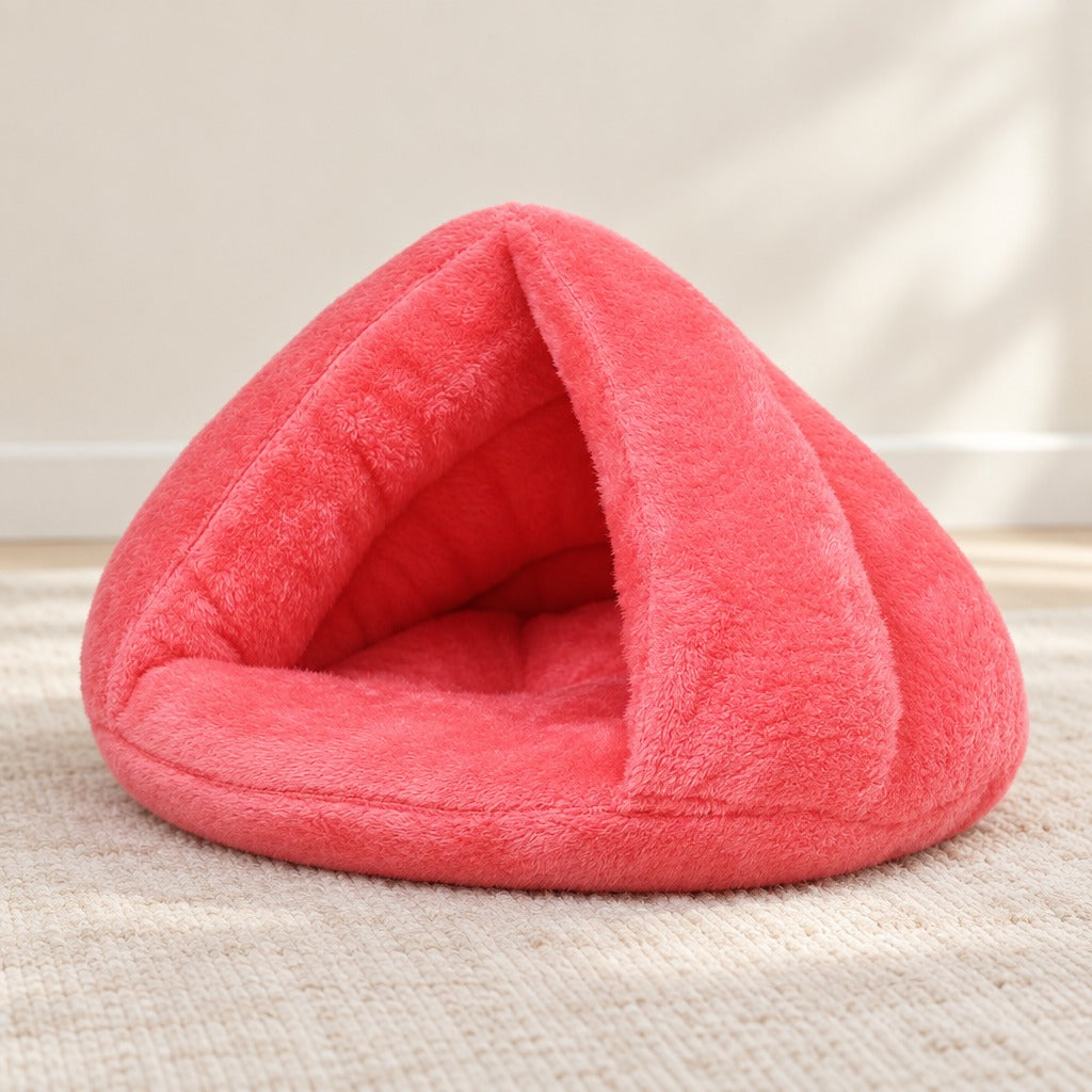 Nid cabane pour chat en peluche corail posé seul sur un tapis clair dans une pièce lumineuse.
