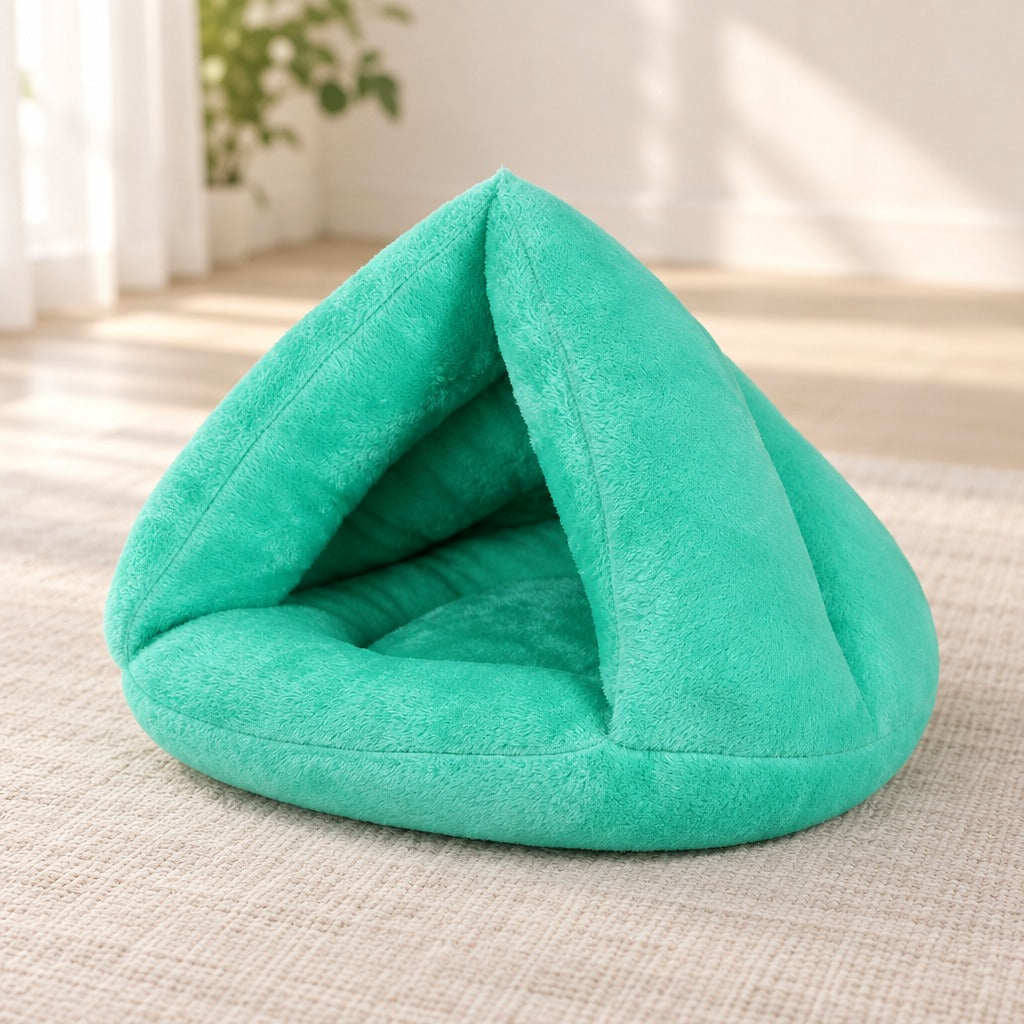 Nid cabane pour chat en peluche vert jade posé seul sur un tapis clair dans un salon lumineux.