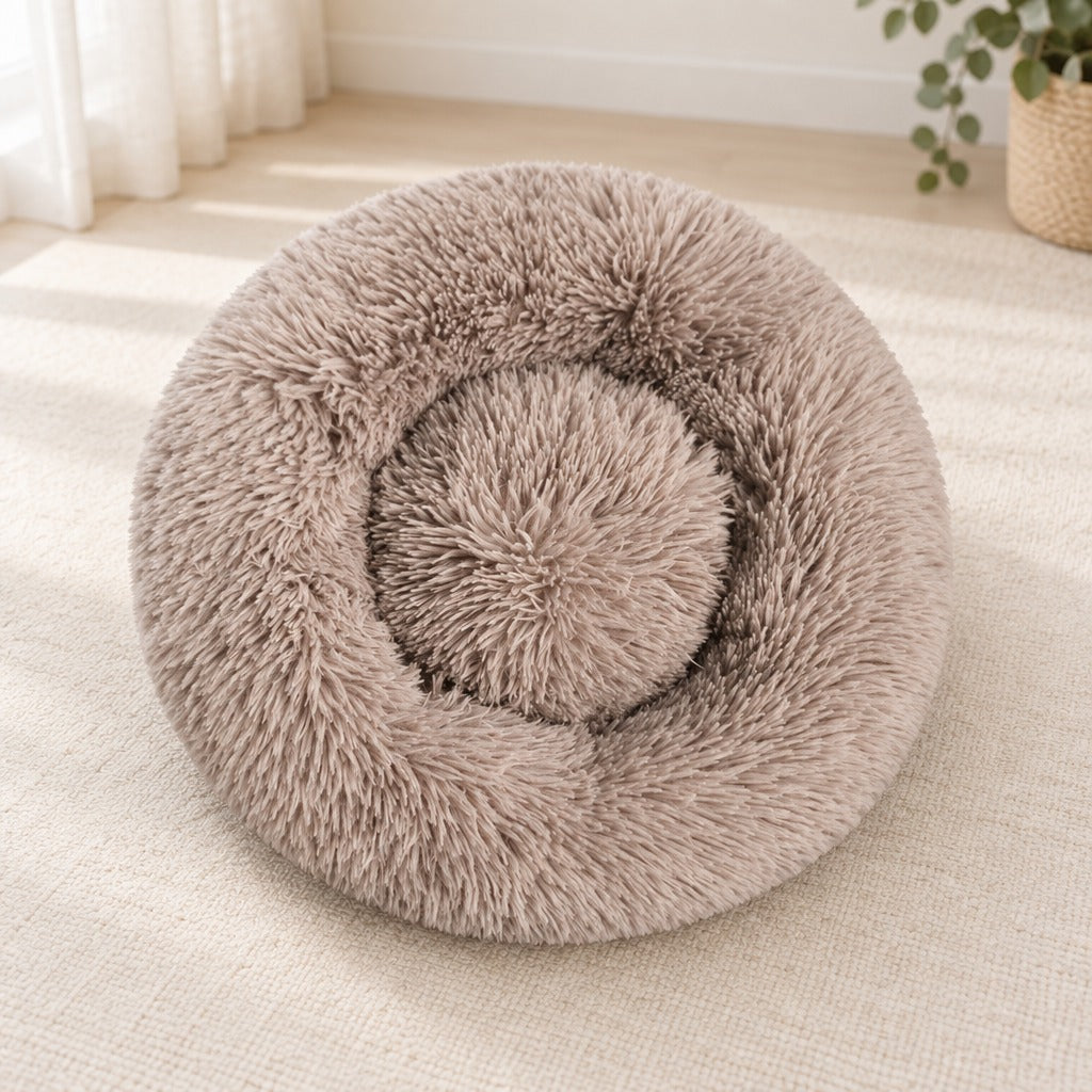 Le panier rond taupe seul sur un sol clair, vu de trois quarts, son bourrelet continu et son creux central plat.