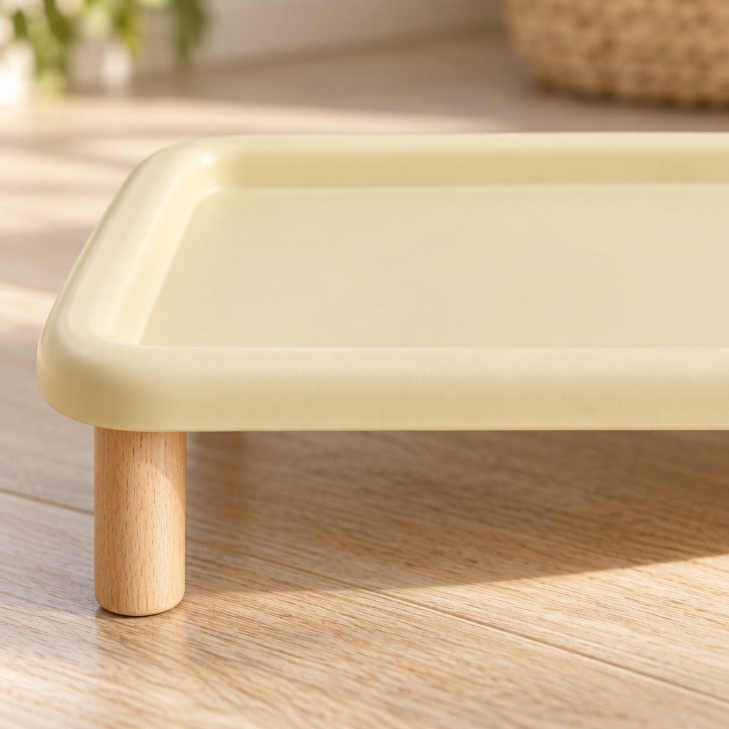 Gros plan sur le bord relevé arrondi du plateau jaune vanille et sur le haut d'un pied cylindrique en bois clair.