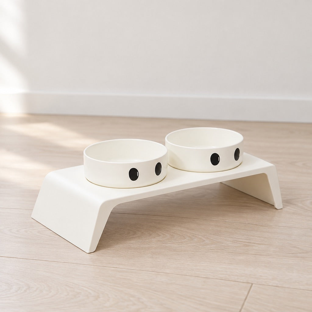Le socle repas modèle Grands yeux, tout blanc seul sur un parquet clair, ses deux bols blancs à l'intérieur comme à l'extérieur.