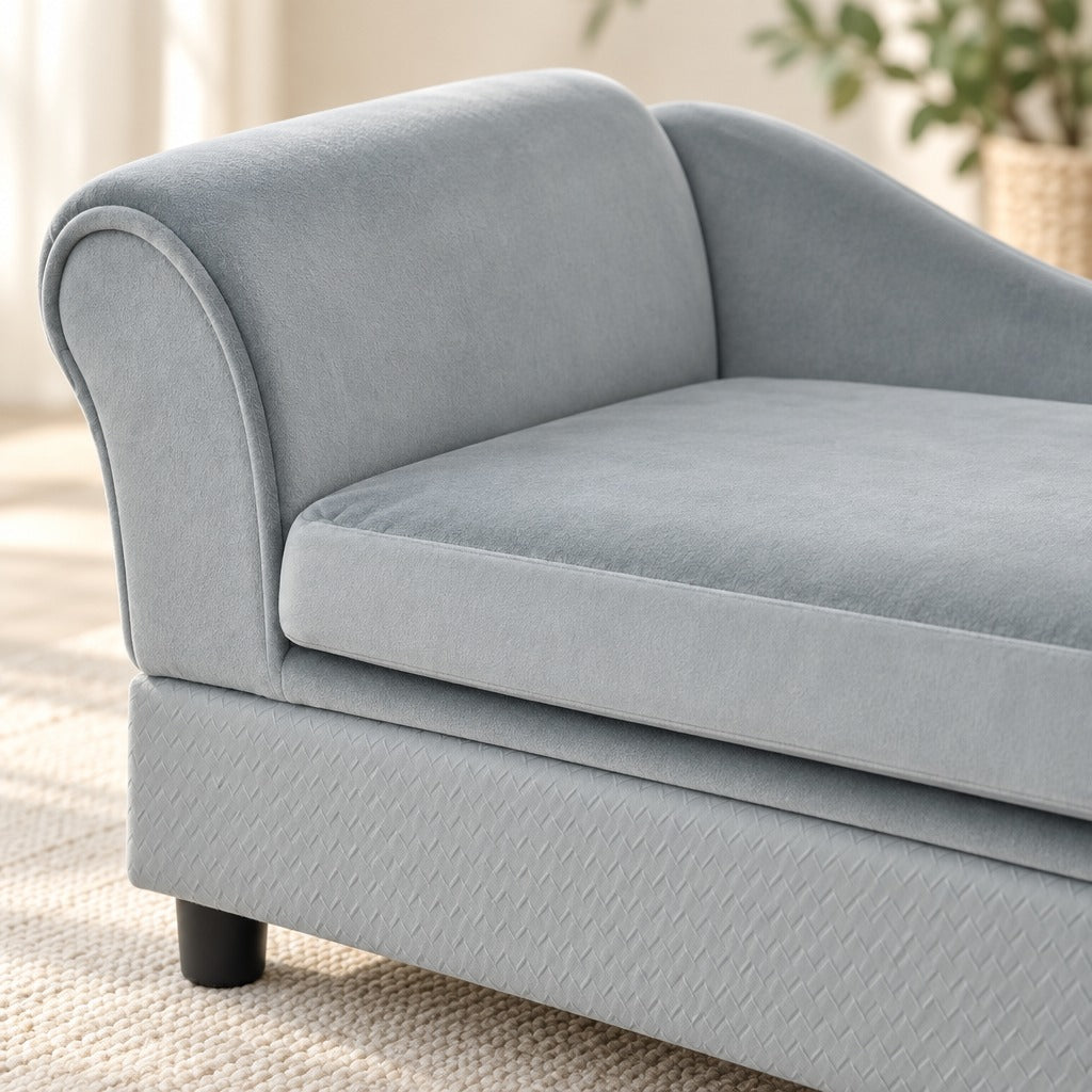 Gros plan sur l'accoudoir enroulé et le coussin gris clair du sofa, le velours ras et le gaufrage en losanges du caisson bien lisibles.