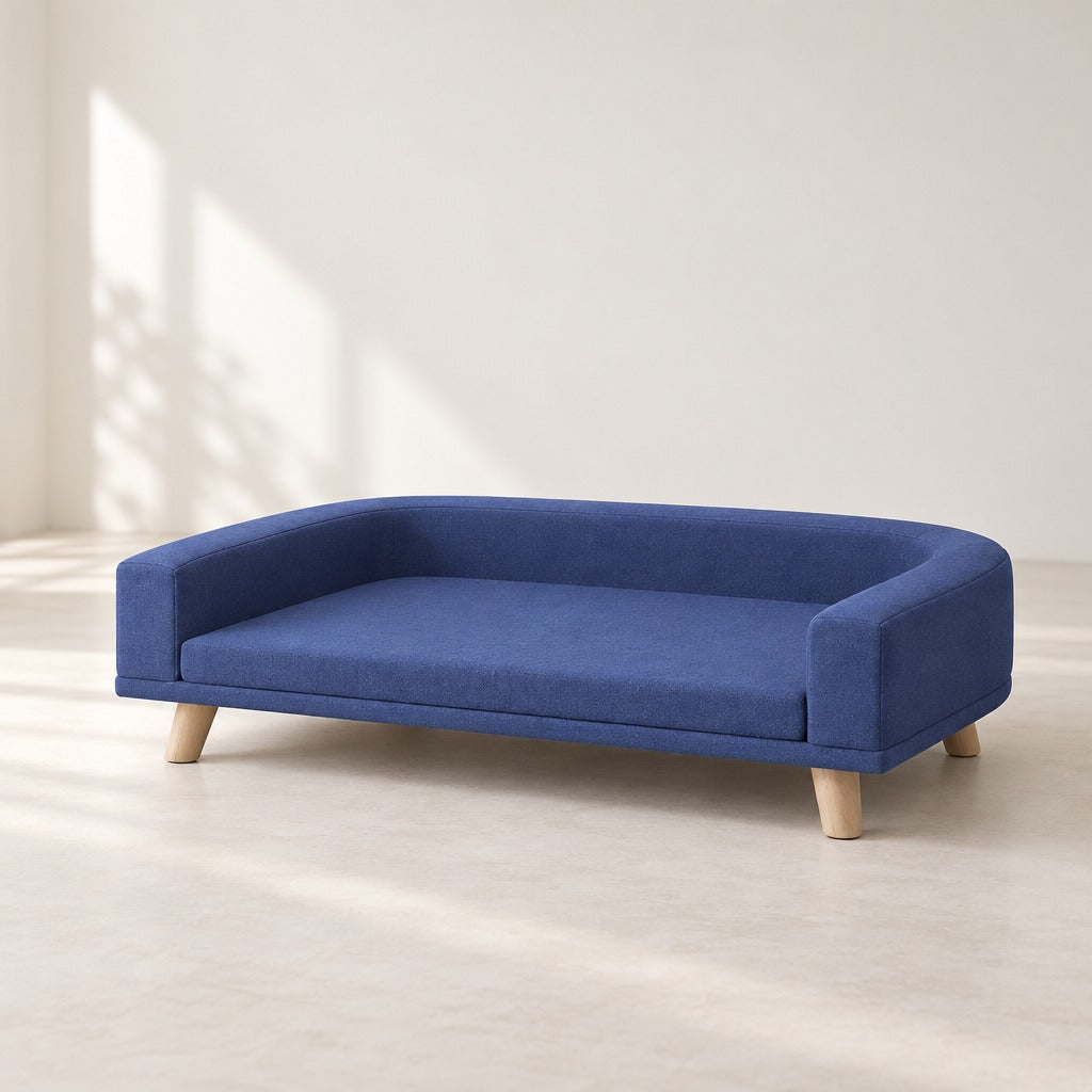 Le sofa pour chien bleu nuit vu seul de trois quarts sur fond clair, son côté avant ouvert et ses quatre pieds coniques en bois clair