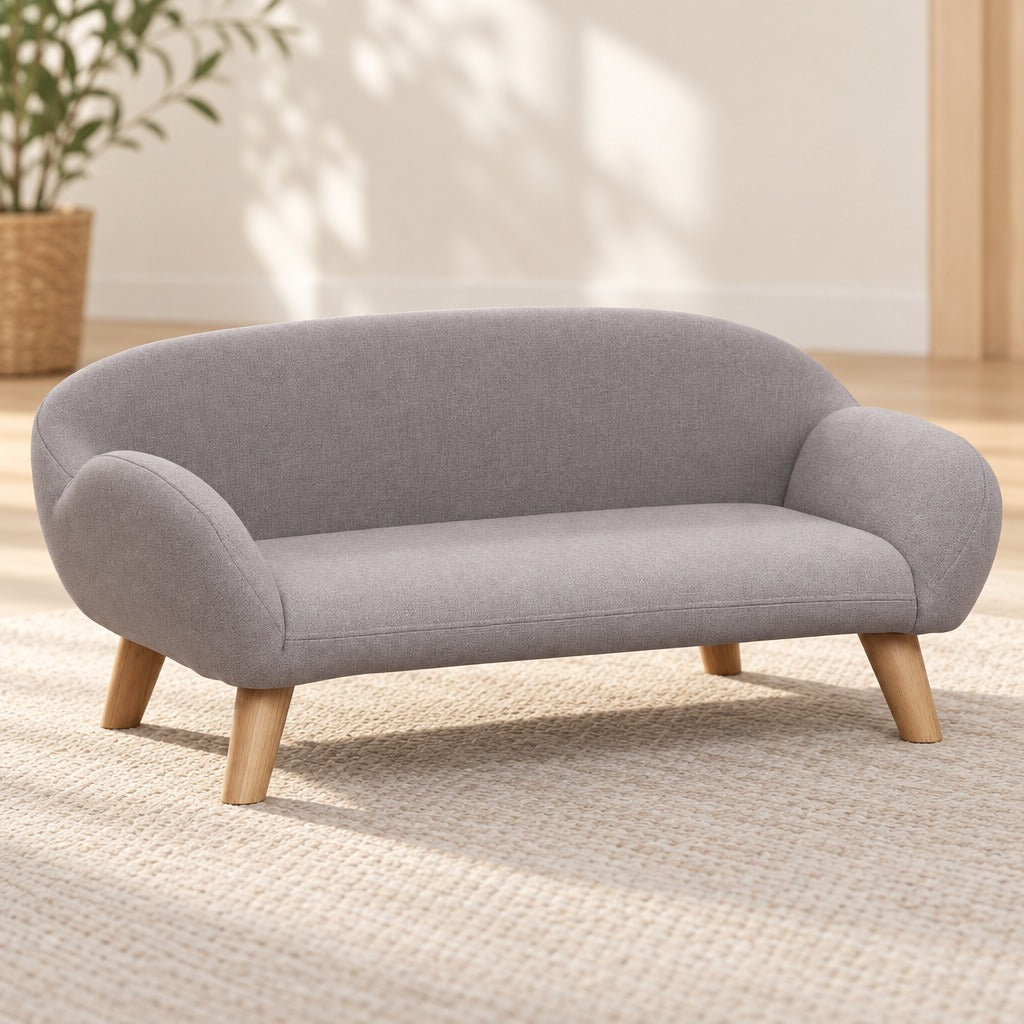 Le sofa pour chien gris clair seul et vide, vu de trois quarts, ses quatre pieds en bois clair bien visibles.