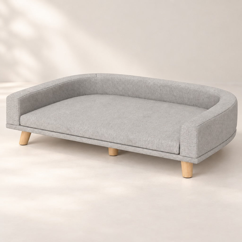 Banquette pour chien gris perle vue de trois quarts, seule sur fond neutre clair.