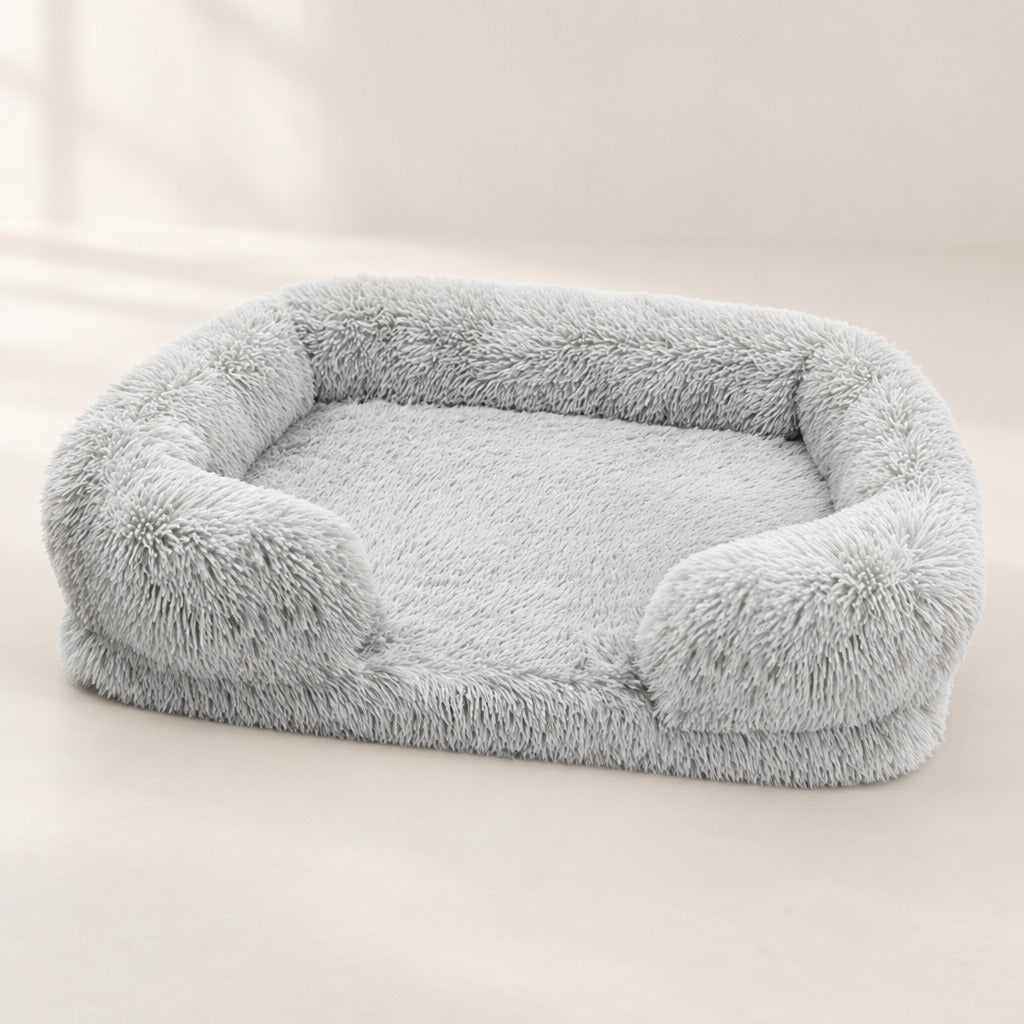 Le sofa gris perle seul sur un fond clair, rebord sur le dos et les deux côtés, avant bas et ouvert entre deux accoudoirs courts.