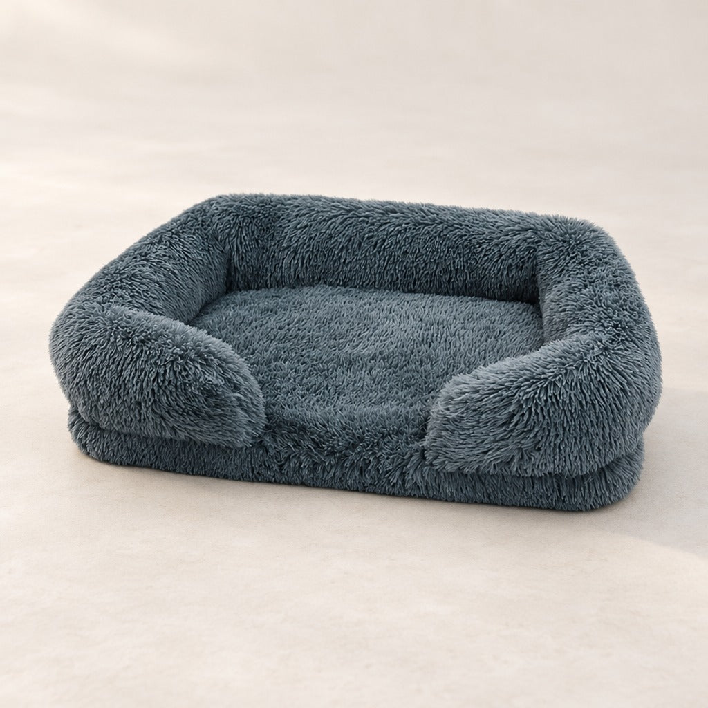 Le sofa gris ardoise seul sur un fond clair, son assise plate encadrée par le rebord arrière et les deux accoudoirs.