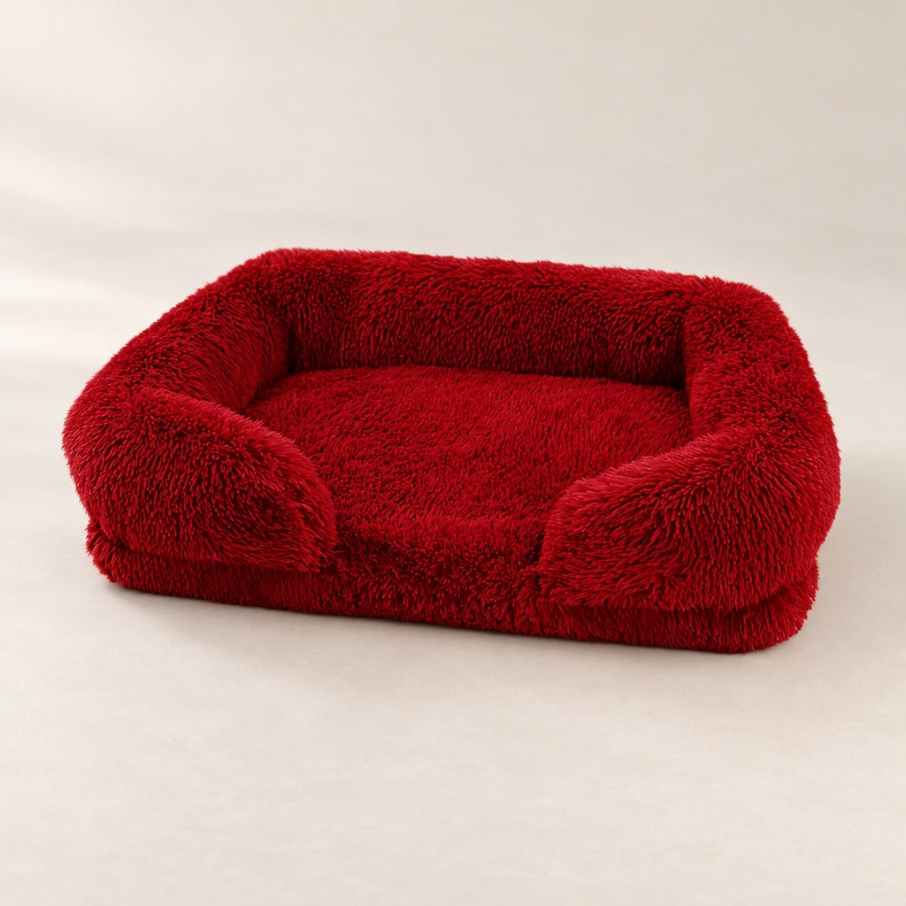 Le sofa rouge bordeaux seul sur un fond clair, son assise plate d'un seul tenant bien visible entre les accoudoirs.