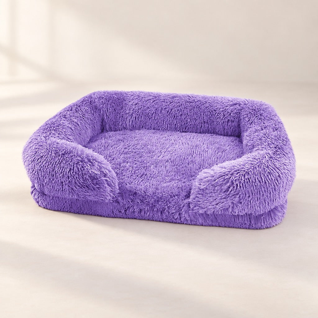 Le sofa parme seul sur un fond clair, rebord sur le dos et les deux côtés et avant bas entre deux accoudoirs courts.