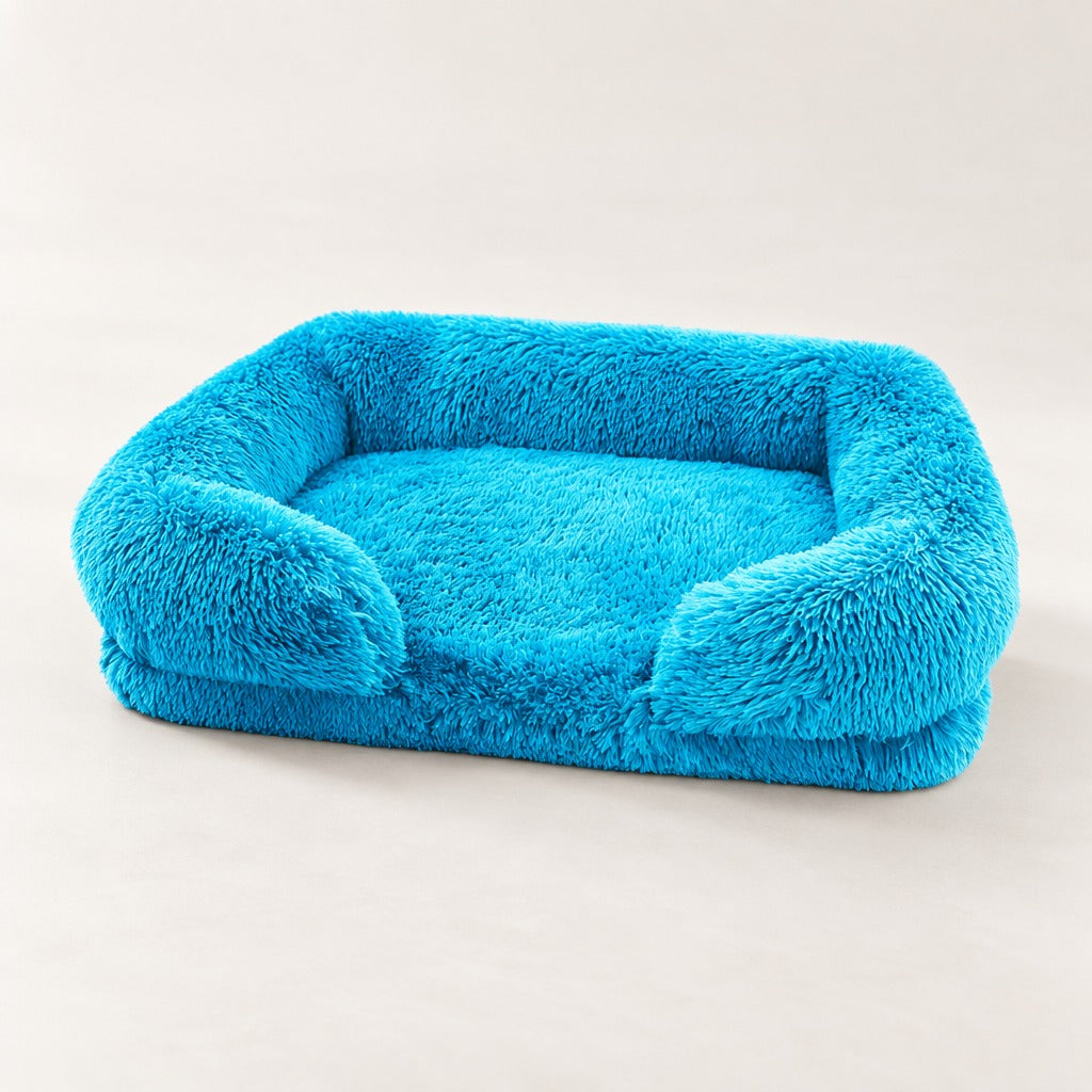 Le sofa bleu turquoise seul sur un fond clair, son assise plate encadrée par le rebord et les deux accoudoirs.