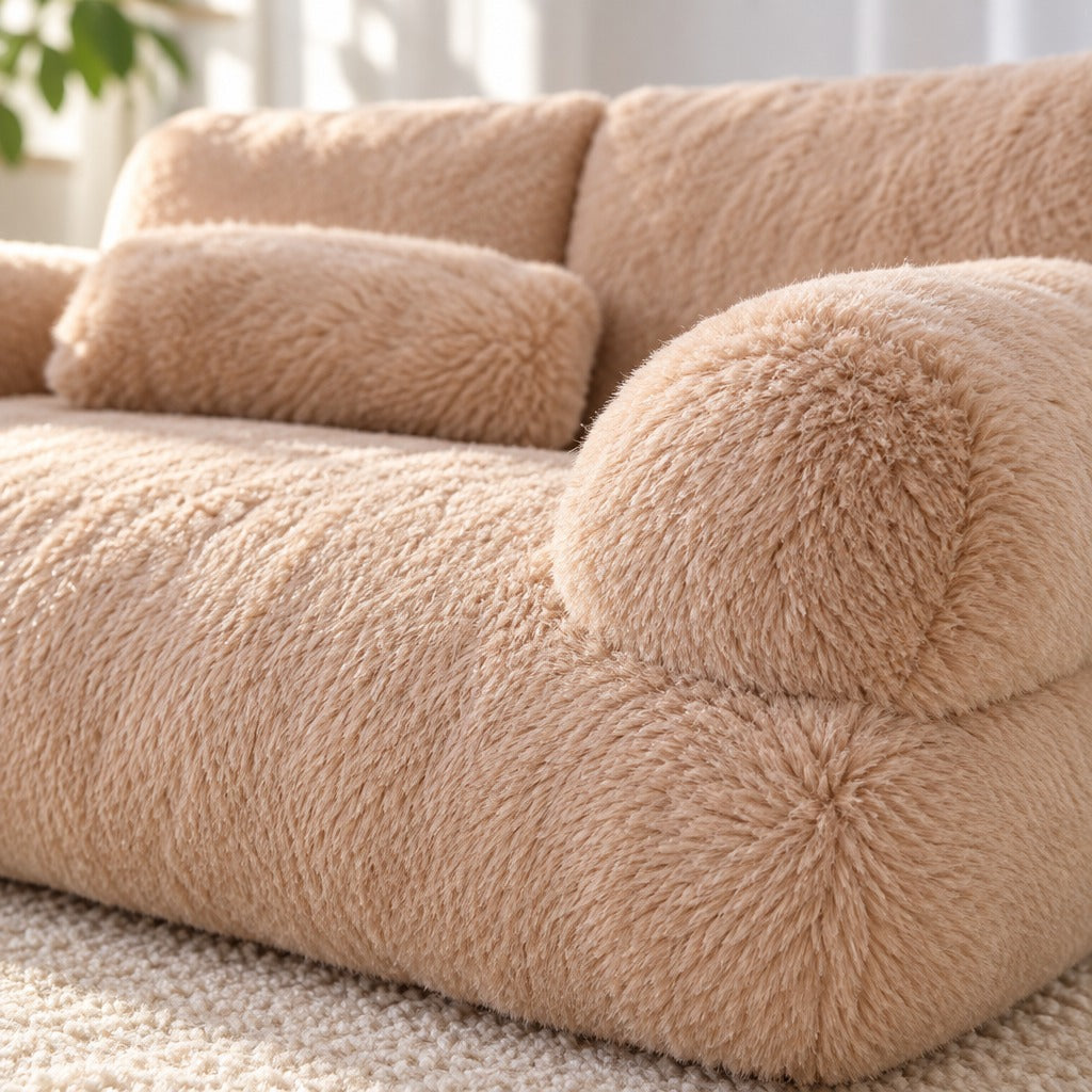 Gros plan sur la peluche à poil long du sofa moelleux moka, le lobe rond d'un accoudoir et le bourrelet de l'assise