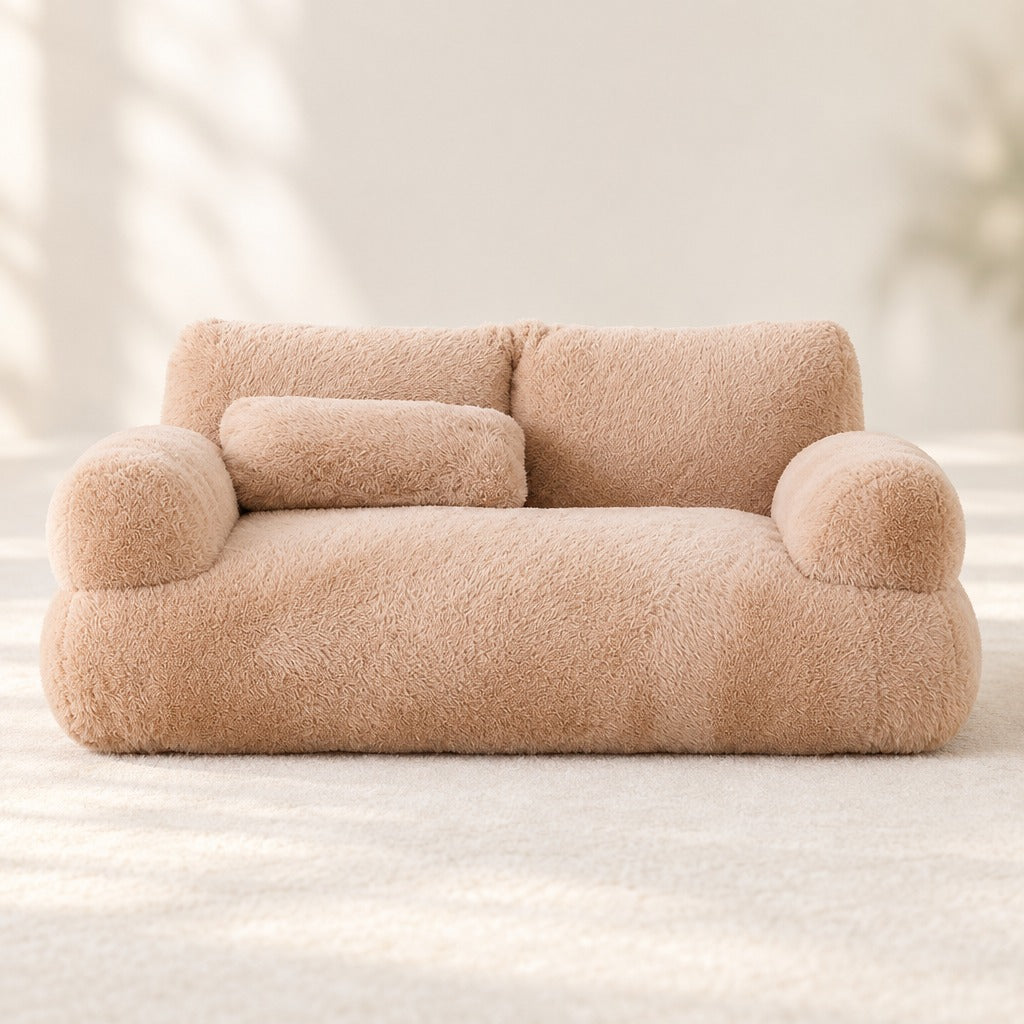 Le sofa moelleux moka vu de face en entier, ses deux accoudoirs ronds, son dossier bas et son traversin posé sur l'assise