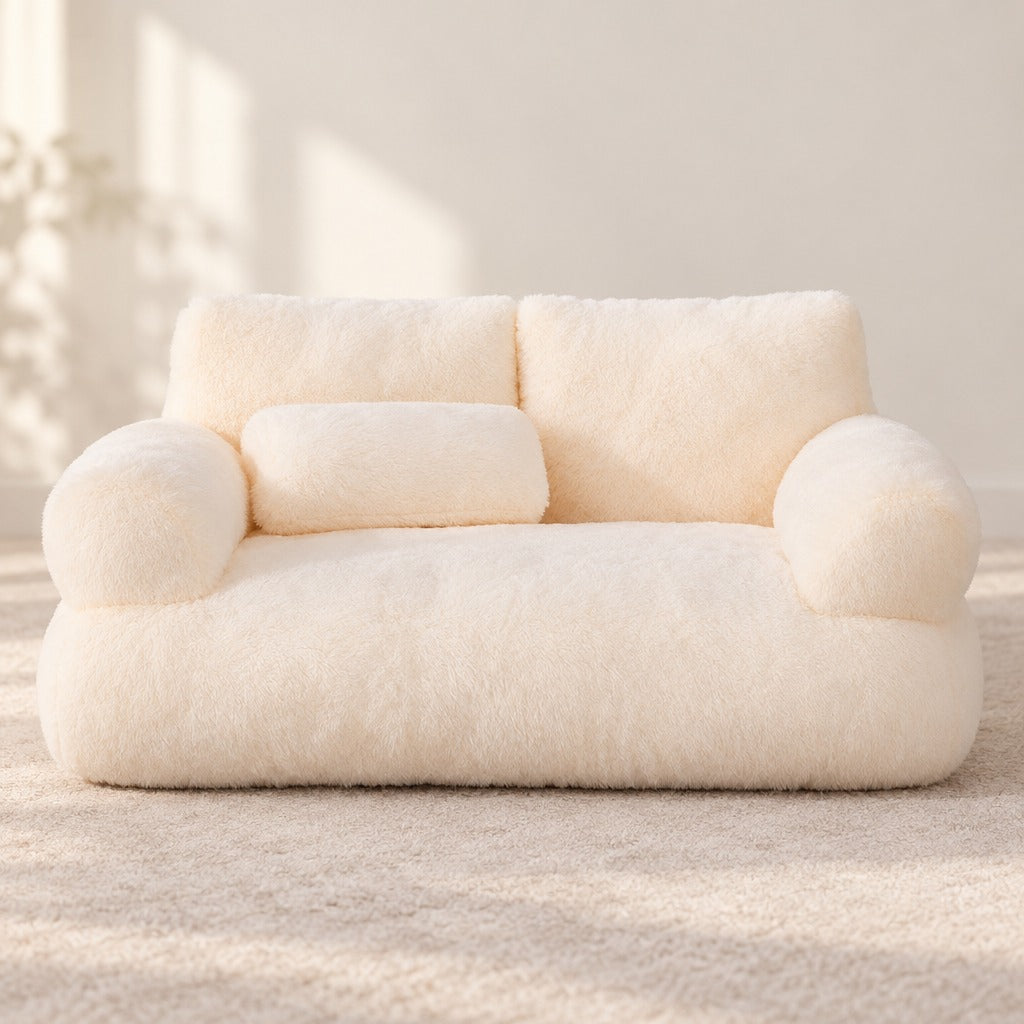 Le sofa moelleux crème vu de face en entier, son dossier bas à deux coussins et son traversin posé sur l'assise