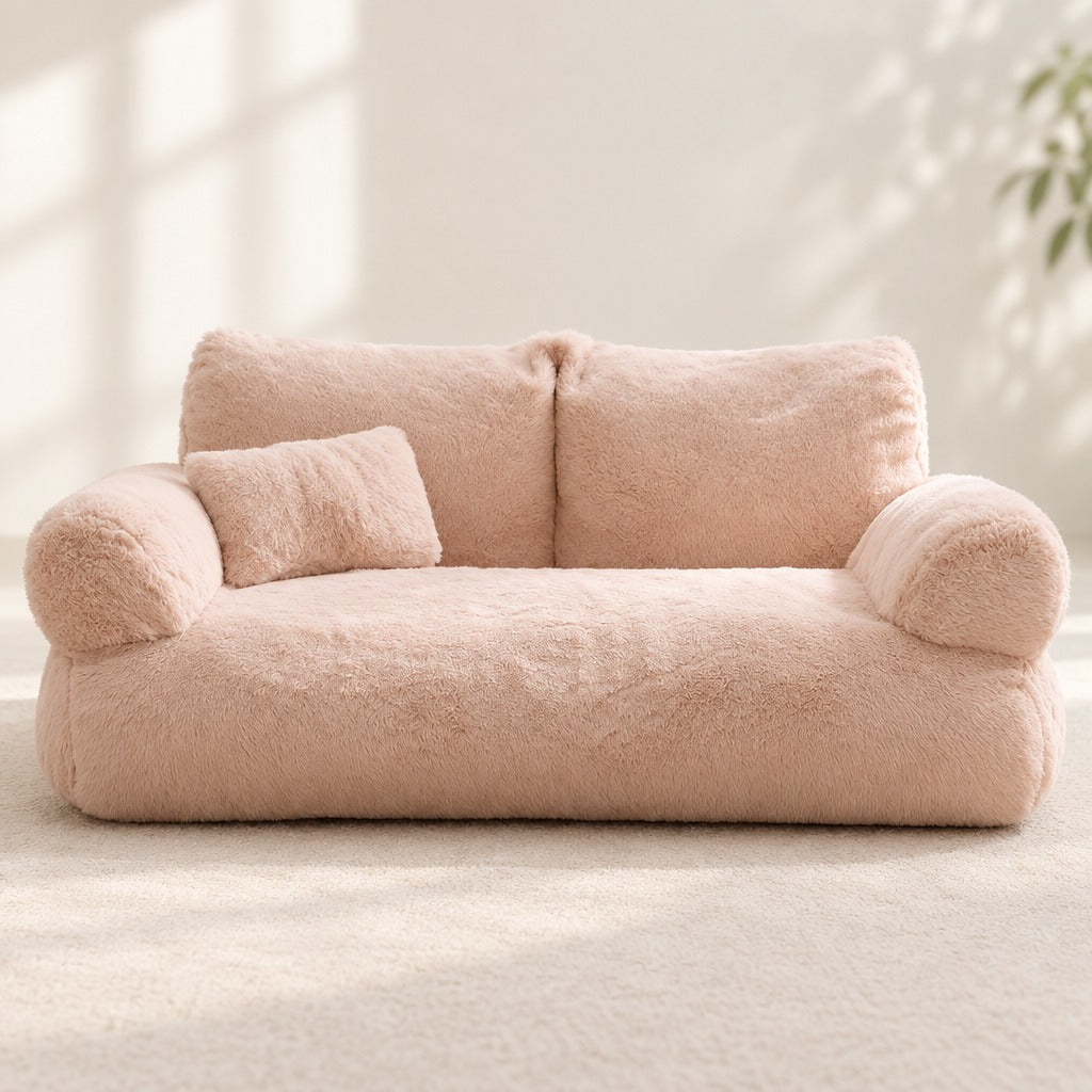 Le sofa moelleux abricot vu de face en entier, ses deux accoudoirs ronds et son traversin posé sur l'assise