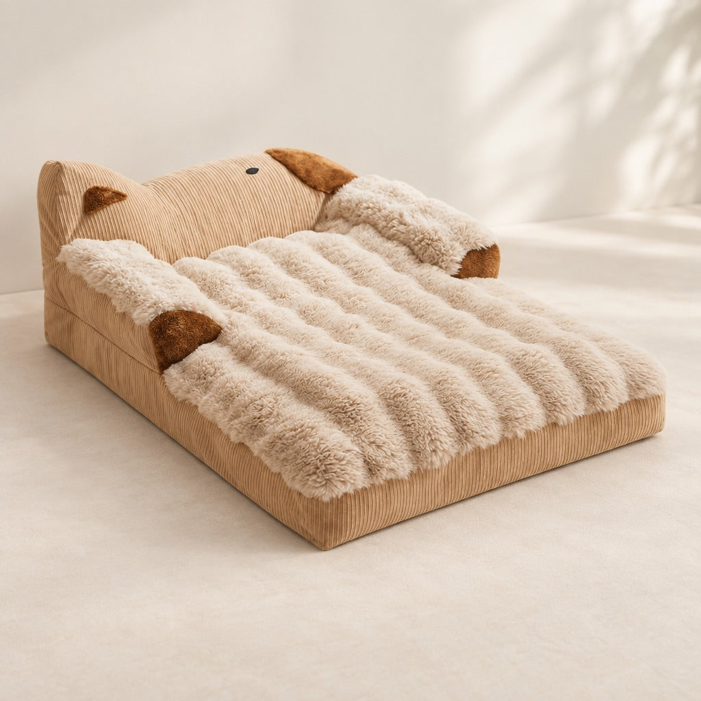 Sofa en peluche pour chien, coloris camel, seul et vu de trois quarts sur un fond clair, ses deux oreilles et ses deux coussinets bruns visibles.