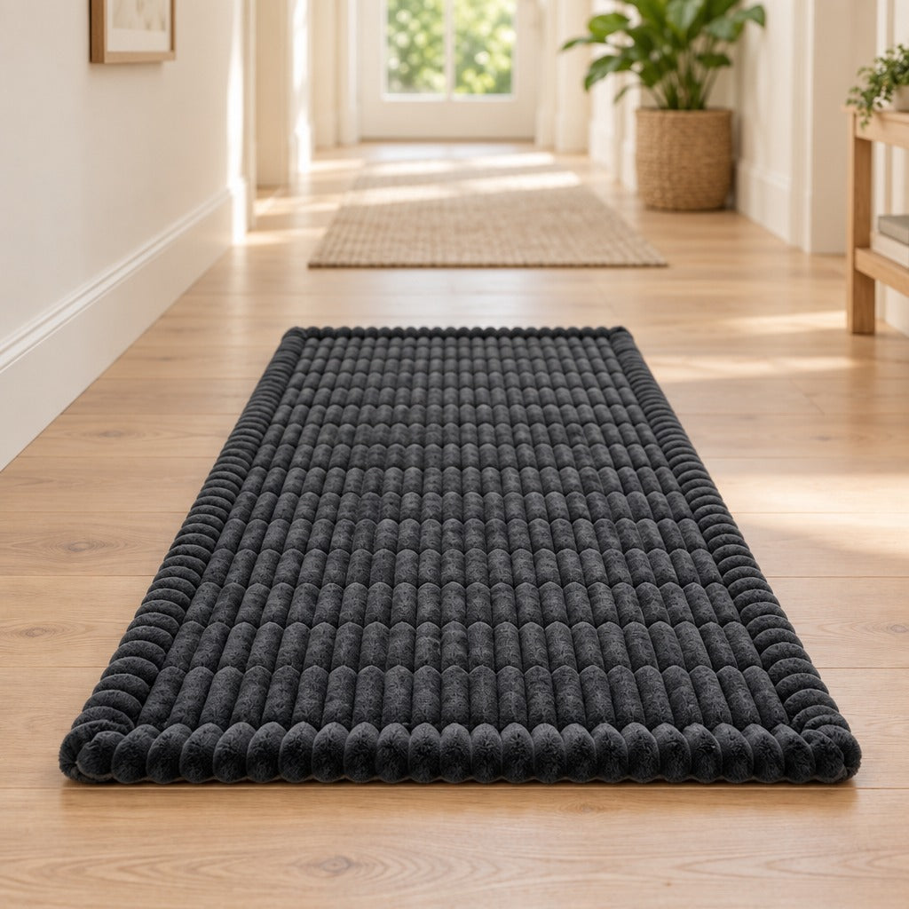 Le tapis gris anthracite seul, posé à plat sur le parquet clair d'un couloir.