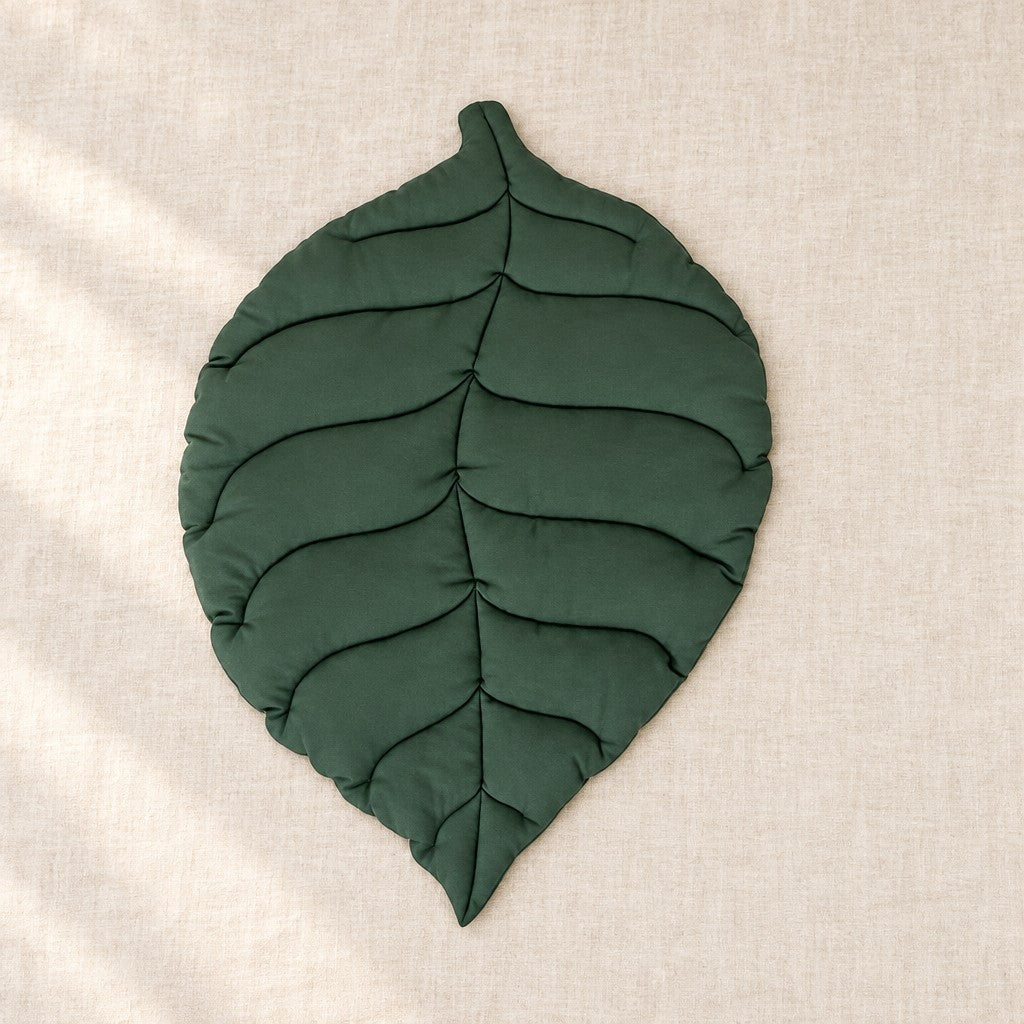 Tapis feuille ovale vert foncé, étalé à plat sur une toile de lin naturelle