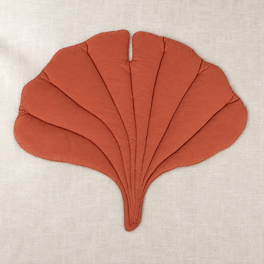 Tapis feuille de ginkgo terracotta, étalé à plat sur une toile de lin naturelle
